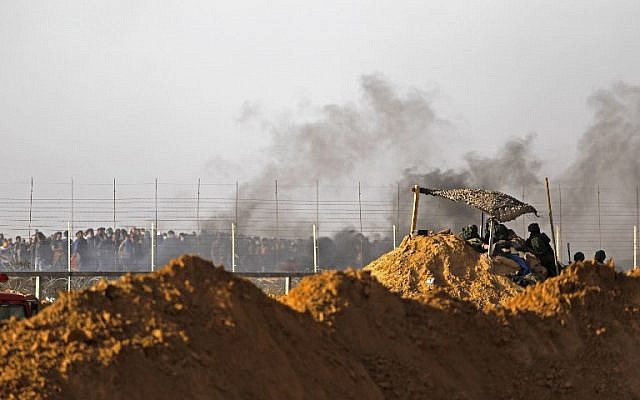 Les forces israéliennes déployées aux abords du Kibbutz Kerem Shalom sur la frontière israélienne au sud de la bande de Gaza alors que la fumée de pneus brûlés par les Palestiniens se dégage, le 6 avril 2018 (Crédit : AFP PHOTO / MENAHEM KAHANA Les forces israéliennes déployées aux abords du Kibbutz Kerem Shalom sur la frontière israélienne au sud de la bande de Gaza alors que la fumée de pneus brûlés par les Palestiniens se dégage, le 6 avril 2018 (Crédit : AFP PHOTO / MENAHEM KAHANA