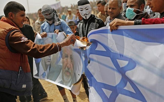 Les Palestiniens s'apprêtent à mettre le feu sur un drapeau israélien et des portraits du ministre de la Défense Avigdor Liberman et du Premier ministre Benjamin Netanyahu lors d'une manifestation à la frontière avec Israël, à l'est de Khan Yunis dans le sud de Gaza le 13 avril 2018 (Crédit : AFP PHOTO / Thomas COEX)