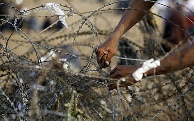 Un Palestinien tente de couper des fils barbelés à la barrière frontalière avec Israël, à l'est de Jabalia dans le centre de la ville de Gaza, lors d'une manifestation le 13 avril 2018 (AFP PHOTO / MOHAMMED ABED).