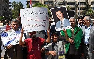 Des Syriens brandissent le drapeau national et des portraits du président Bashar el-Assad, sur la place Saadallah al-Jabiri, à Alep, le 14 avril 2018, pour condamner les frappes menées par les Etats-Unis, la France et la Grande Bretagne contre le régime syrien. (Crédit : AFP / George OURFALIAN) Des Syriens brandissent le drapeau national et des portraits du président Bashar el-Assad, sur la place Saadallah al-Jabiri, à Alep, le 14 avril 2018, pour condamner les frappes menées par les Etats-Unis, la France et la Grande Bretagne contre le régime syrien. (Crédit : AFP / George OURFALIAN)
