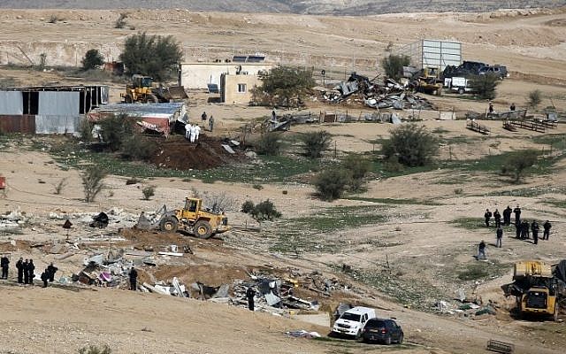 Des policiers israéliens montent la garde alors que des bulldozers démolissent des maisons dans le village bédouin illégal d'Oum al-Hiran, dans le désert du Néguev, le 18 janvier 2017. (AFP Photo/Menahem Kahana) Des policiers israéliens montent la garde alors que des bulldozers démolissent des maisons dans le village bédouin illégal d'Oum al-Hiran, dans le désert du Néguev, le 18 janvier 2017. (AFP Photo/Menahem Kahana)