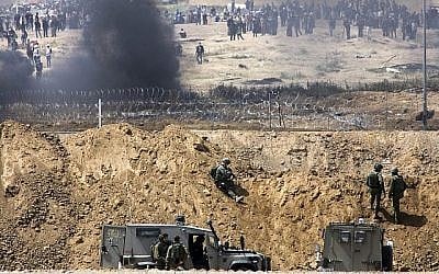 Des manifestants palestiniens brûlent des pneus près de la frontière avec Israël dans la bande de Gaza, vu du côté israélien de la frontière, le 13 avril 2018. (Sliman Khader/Flash90) Des manifestants palestiniens brûlent des pneus près de la frontière avec Israël dans la bande de Gaza, vu du côté israélien de la frontière, le 13 avril 2018. (Sliman Khader/Flash90)