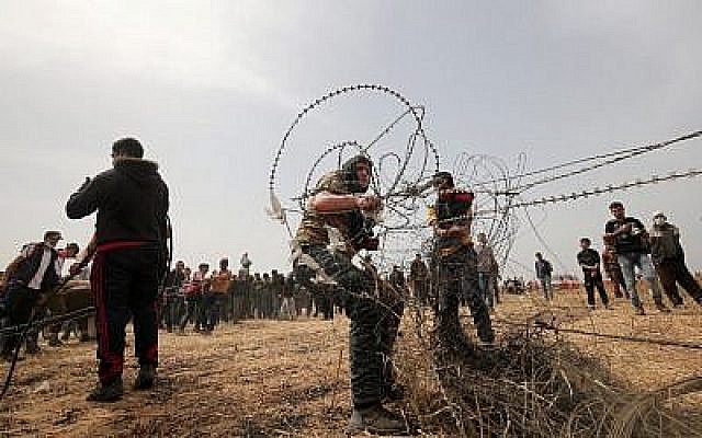 Photo d'illustration. Des Palestiniens arrachent du fil barbelé de la clôture frontalière avec Israël durant les affrontements hebdomadaires du vendredi à Rafah, dans le sud de la bande de Gaza, le 20 avril 2018 (Crédit : AFP Photo/Said Khatib) Photo d'illustration. Des Palestiniens arrachent du fil barbelé de la clôture frontalière avec Israël durant les affrontements hebdomadaires du vendredi à Rafah, dans le sud de la bande de Gaza, le 20 avril 2018 (Crédit : AFP Photo/Said Khatib)
