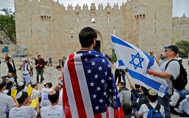 Un Israélien endosse le drapeau américain devant la porte de Damas, dans la Vieille Ville de Jérusalem, le 13 mai 2018. (Crédit : AFP / Ahmad GHARABLI)