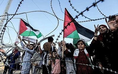 Une fille brandit un drapeau palestinien alors qu'un autre garçon palestinien tient une clé en bois symbolisant le retour, alors qu'ils se tiennent aux côtés d'autres personnes devant le fil barbelé marquant la frontière entre la bande de Gaza et Israël à l'est de la ville de Gaza le 13 mai 2018. (AFP/Mahmud Hams) Une fille brandit un drapeau palestinien alors qu'un autre garçon palestinien tient une clé en bois symbolisant le retour, alors qu'ils se tiennent aux côtés d'autres personnes devant le fil barbelé marquant la frontière entre la bande de Gaza et Israël à l'est de la ville de Gaza le 13 mai 2018. (AFP/Mahmud Hams)