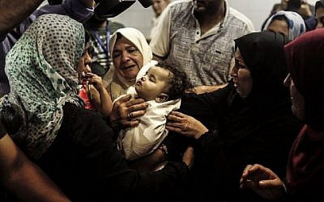 Des proches de Leila al-Ghandour, un bébé palestinien de 8 mois qui, selon le ministère de la Santé de Gaza, dirigé par le Hamas, est mort par inhalation de gaz lacrymogène lors des affrontements dans l'est de Gaza la veille, la gardent à la morgue de l'hôpital al-Shifa dans la ville de Gaza le 15 mai 2018. Un médecin de Gaza, qui a indiqué qu'elle avait des problèmes de santé préexistants, et Israël ont contesté les circonstances de sa mort. (AFP/Mahmud Hams)