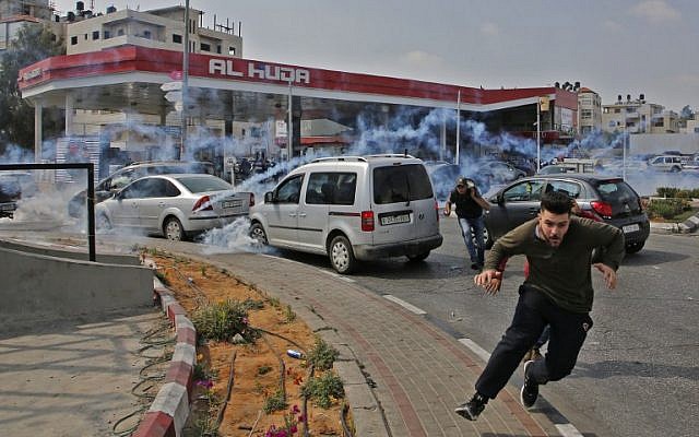 Des Palestiniens fuient les gaz lacrymogènes lancés par les forces israéliennes durant une manifestation à Ramallah, en Cisjordanie, le 15 mai 2018 (Crédit : AFP/ABBAS MOMANI) Des Palestiniens fuient les gaz lacrymogènes lancés par les forces israéliennes durant une manifestation à Ramallah, en Cisjordanie, le 15 mai 2018 (Crédit : AFP/ABBAS MOMANI)