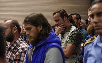 Besart Peci, à droite, un extrémiste musulman condamné pour avoir planifié un attentat contre la sélection de football israélienne, fait un geste aux côtés de ses complices devant un tribunal de Pristina, au Kosovo, le 18 mai 2018  (Crédit : / AFP PHOTO / Armend NIMANI)