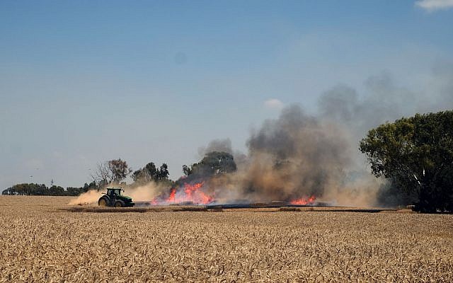 Illustration : Un agriculteur israélien éteint un incendie dans son champ qui a été allumé par un cerf-volant incendiaire envoyé de Gaza aux abords du kibboutz de Nahal Oz, dans le sud d'Israël, le 14 mai 2018 (Crédit :  Judah Ari Gross/Times of Israel)