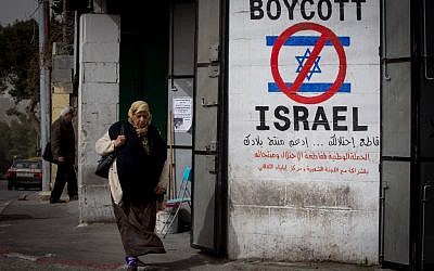 Une Palestinienne marche devant une pancarte appelant au boycott d'Israël dans la ville de Bethléem en Cisjordanie, le 11 février 2015 (Miriam Alster / Flash 90)