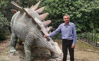 Le Dr Evgeny Reznitsky, directeur pédagogique du Musée d'histoire naturelle de Jérusalem, debout à côté d'une statue de dinosaure dans le jardin extérieur du musée le 1er mai 2018. (Michael Bachner/Times of Israel)