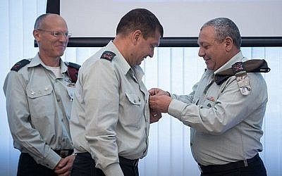 Le chef d'Etat-major Gadi Eizenkot place  son insigne sur la chemise de nouveau chef des opérations de l'armée israélienne, le général de division Aharon Haliva, alors que le chef sortant, le général de division Nitzan Alon les regarde, durant une cérémonie organisée au siège de l'armée, à Tel Aviv, le 21 mai 2018 (Crédit : Armée israélienne)