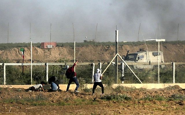 Un Palestinien jette des pierres sur les forces israéliennes alors que de la fumée s'élève des pneus brûlés durant une manifestation le long de la frontière avec la bande de Gaza, à l'est de Gaza city, le 1er juin 2018 (Crédit :  / AFP PHOTO / Mahmud Hams)