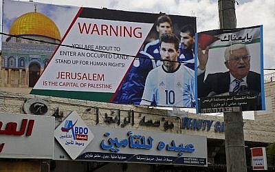 Cette photo du 5 juin 2018 montre une affiche érigée dans la ville de Hébron, en Cisjordanie, appelant au boycott de la star du football Lionel Messi (g) à côté d'un portrait du président de l'Autorité palestinienne Mahmoud Abbas. (AFP PHOTO / HAZEM BADER)