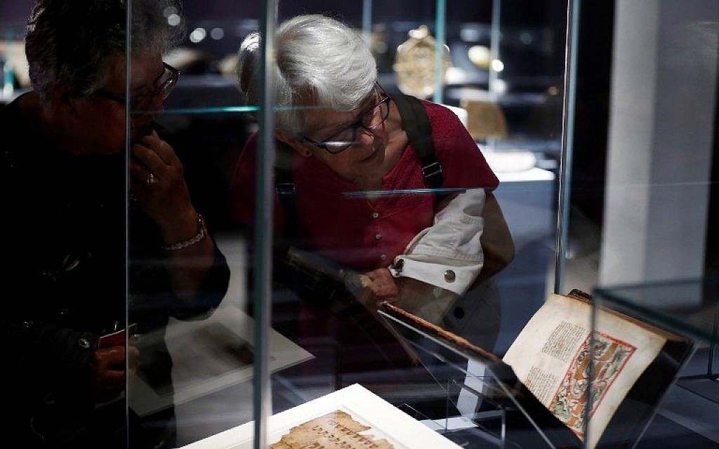 Les visiteurs regardent un livre historique présenté dans l'exposition "Savants et croyants, les Juifs d'Europe du Nord au Moyen-Age" au musée des Antiquités de Rouen, en France, le 7 juin 2018. (Crédit : AFP / CHARLY TRIBALLEAU)