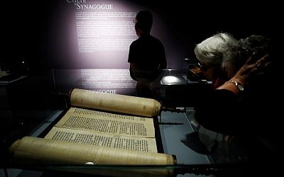 Les visiteurs regardent un rouleau de Torah présenté dans l'exposition "Savants et croyants, les Juifs d'Europe du Nord au Moyen-Age" au musée des Antiquités de Rouen, en France, le 7 juin 2018. (Crédit : AFP / CHARLY TRIBALLEAU)