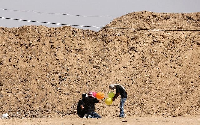 Des manifestants palestiniens tiennent des ballons avant de les charger de matériel inflammable vers Israël à la frontière israélo-gazaouie à al-Bureij, dans le centre de la bande de Gaza, le 14 juin 2018 (Crédit : AFP PHOTO / MAHMUD HAMS) Des manifestants palestiniens tiennent des ballons avant de les charger de matériel inflammable vers Israël à la frontière israélo-gazaouie à al-Bureij, dans le centre de la bande de Gaza, le 14 juin 2018 (Crédit : AFP PHOTO / MAHMUD HAMS)