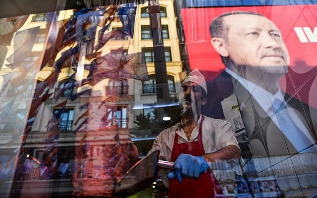 Tandis qu'un boucher tranche de la viande, l'on aperçoit le reflet d'un portrait du président turc Recep Tayyip Erdogan dans la fenêtre d'un restaurant turc sur la place Taksim d'Istanbul le 20 juin 2018. (Crédit : AFP / Bulent Kilic) Tandis qu'un boucher tranche de la viande, l'on aperçoit le reflet d'un portrait du président turc Recep Tayyip Erdogan dans la fenêtre d'un restaurant turc sur la place Taksim d'Istanbul le 20 juin 2018. (Crédit : AFP / Bulent Kilic)