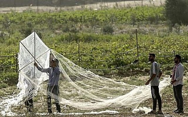Des Palestiniens préparent un cerf-volant chargé de matériel inflammable pour qu'il puisse traverser la frontière entre la bande de Gaza et Israël, à l'est de la ville de Gaza, le 22 juin 2018. (AFP Photo/Mahmud Hams)