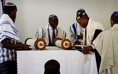 Le rabbin Gershom, (second à gauche), se prépare à la lecture de la Torah pendant un office de Shabbat au sein de la communauté juive Abayudaya dans un village proche de Mbalé, à l'est de l'Ouganda, le 2 juillet 2016 (Crédit : AFP/Michael O’Hagan)