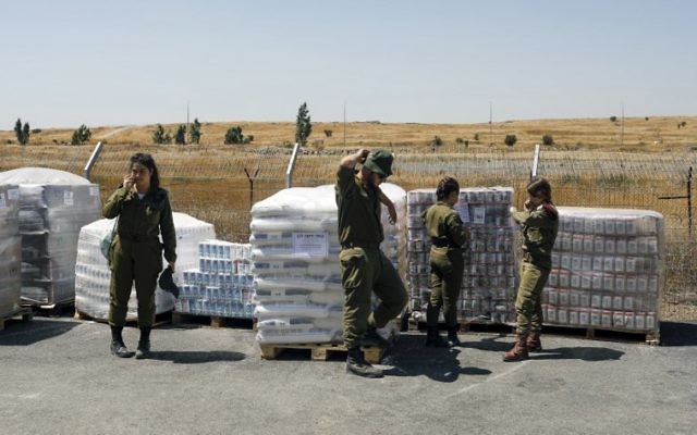 Des soldats de Tsahal se tiennent à côté des vivres en cours de préparation dans le cadre de l'aide humanitaire pour les Syriens touchés par la guerre civile dans leur pays, le 19 juillet 2017. (AFP/Menahem Kahana) Des soldats de Tsahal se tiennent à côté des vivres en cours de préparation dans le cadre de l'aide humanitaire pour les Syriens touchés par la guerre civile dans leur pays, le 19 juillet 2017. (AFP/Menahem Kahana)