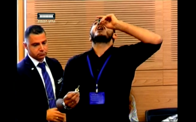 Un homme avale une bouteille d'huile de cannabis pendant une réunion de la commission de la Santé à la Knesset (Capture d'écran) Un homme avale une bouteille d'huile de cannabis pendant une réunion de la commission de la Santé à la Knesset (Capture d'écran)