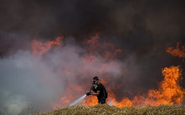 Les pompiers éteignent un feu dans un champ de blé qui avait été allumé par des cerfs-volants incendiaires depuis la bande de Gaza en Israël, le 30 mai 2018 (Crédit : Yonatan Sindel/Flash90)