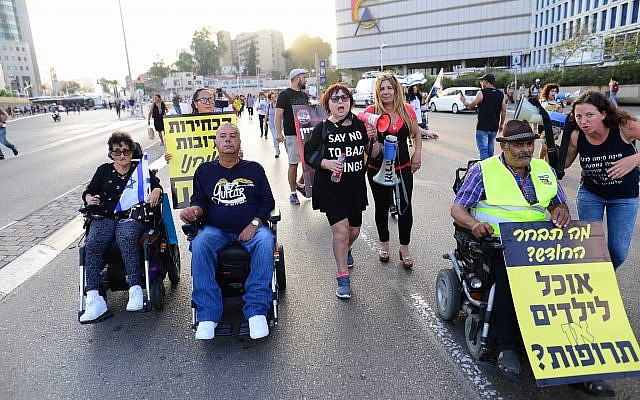 Des personnes handicapées, des invalides et des activistes bloquent une route alors qu'ils prennent part à une manifestation pour réclamer de meilleurs soins de santé et de meilleures allocations à Tel Aviv le 31 mai 2018. (Photo : Tomer Neuberg/Flash90) Des personnes handicapées, des invalides et des activistes bloquent une route alors qu'ils prennent part à une manifestation pour réclamer de meilleurs soins de santé et de meilleures allocations à Tel Aviv le 31 mai 2018. (Photo : Tomer Neuberg/Flash90)