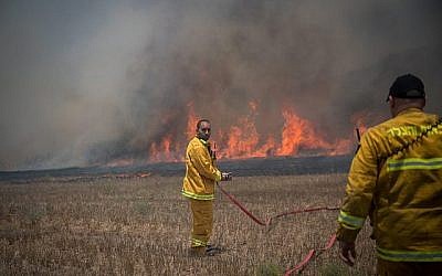 Des pompiers israéliens combattent un incendie dans un champ dans le sud d'Israël causé par des cerfs-volants incendiaires pilotés par des Palestiniens depuis la bande de Gaza le 5 juin 2018. (Crédit : Yonatan Sindel/Flash90)