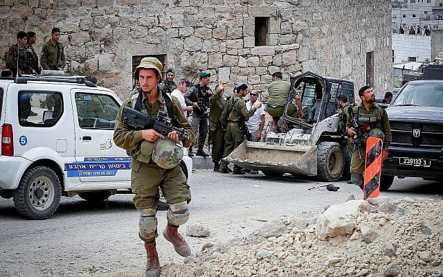 Les soldats israéliens sur les lieux d'une tentative d'attaque au véhicule-bélier dans la ville de Hébron, en Cisjordanie, le 2 juin 2018 (Crédit : Wisam Hashlamoun/Flash90)