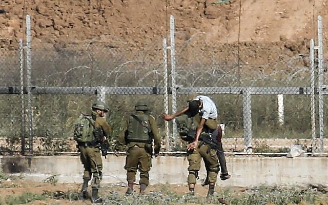 Les soldats israéliens emmènent un Palestinien blessé qui, selon l'armée, aurait tenté d'ouvrir une brèche dans la frontière à l'est de Jabaliya, dans le nord de la bande de Gaza, le 27 juin 2018 (Crédit : Said Khatib/AFP)