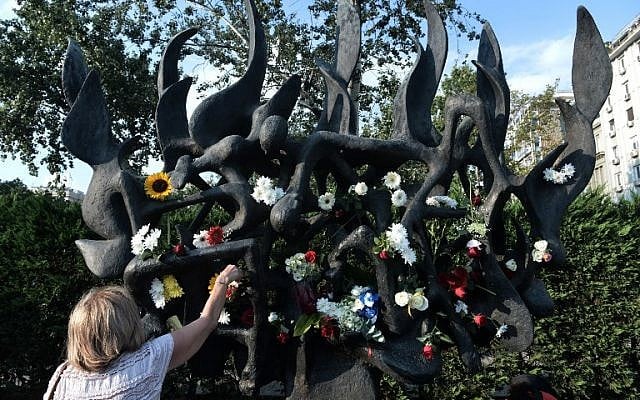 Une femme dépose une rose en signe de protestation contre la profanation d'un mémorial de la Shoah à Thessalonique, le 4 juillet 2018. (Crédit : AFP/Sakis Mitrolidis)