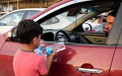 Un enfant irakien vend des bouteilles d'eau à des conducteurs circulant dans une rue de la ville de Mossoul, dans le nord de l'Irak, le 7 juillet 2018. (Crédit : AFP / Waleed AL-KHALID)