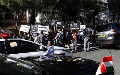 Des manifestants israéliens brandissent des panneaux de l'organisation Amnesty international disant en bloquant la route du convoi transportant le Premier ministre hongrois Viktor Orban au mémorial de la Shoah de Yad Vashem de Jérusalem, le 19 juillet 2018 (Crédit : AFP PHOTO / GALI TIBBON)