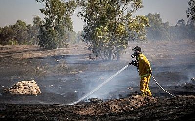 Les pompiers éteignent un incendie dans un champ allumé par des des combustibles attachés à des cerfs-volants envoyés depuis la bande de Gaza par des Palestiniens, le 27 juin 2018 (Crédit : Flash90)