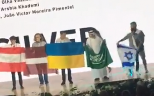 L'étudiant saoudien Badr al-Mulhim, 2ème à droite, est vu avec son drapeau et se préparant à se déplacer à l'arrivée de l'Israélien Raz Lotan, à droite, qui porte les couleurs de l'Etat juif lors de la 50ème édition des olympiades internationales de Chimie, en Slovaquie et en république tchèque, dans une vidéo publiée sur internet le 29 juillet 2018 (Capture d'écran : Twitter) L'étudiant saoudien Badr al-Mulhim, 2ème à droite, est vu avec son drapeau et se préparant à se déplacer à l'arrivée de l'Israélien Raz Lotan, à droite, qui porte les couleurs de l'Etat juif lors de la 50ème édition des olympiades internationales de Chimie, en Slovaquie et en république tchèque, dans une vidéo publiée sur internet le 29 juillet 2018 (Capture d'écran : Twitter)