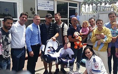 Illustration : les pères de bébés nés de mères porteuses népalaises et conduits en Israël le 27 avril 2015 posent avec le directeur général du Magen David Adom, Eli Bin (deuxième à partir de la gauche) et le ministre de l'Intérieur Gilad Erdan (troisième à partir de la gauche). (Crédit : avec l'aimable autorisation du MDA)