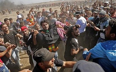 Des Palestiniens portent un manifestant blessé lors d'affrontements avec les forces israéliennes près de la frontière entre la bande de Gaza et Israël, à l'est de la ville de Gaza, le 14 mai 2018 (AFP PHOTO / Thomas COEX) Des Palestiniens portent un manifestant blessé lors d'affrontements avec les forces israéliennes près de la frontière entre la bande de Gaza et Israël, à l'est de la ville de Gaza, le 14 mai 2018 (AFP PHOTO / Thomas COEX)