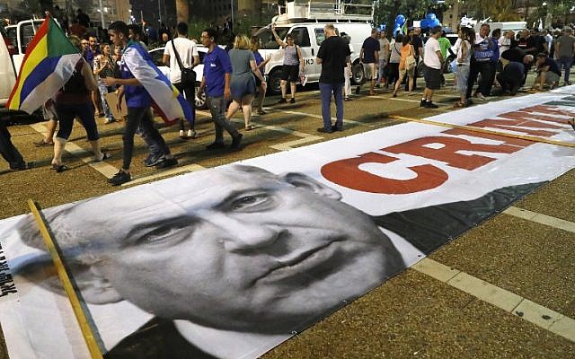 Une bannière avec un message politique et une photo du Premier ministre Benjamin Netanyahu sur le sol alors que les membres de la communauté druze et leurs soutiens manifestent contre la loi sur l'Etat-nation à Tel Aviv, le 4 août 2018. Le message
est "Ministre du crime" (Crédit : AFP PHOTO / JACK GUEZ) Une bannière avec un message politique et une photo du Premier ministre Benjamin Netanyahu sur le sol alors que les membres de la communauté druze et leurs soutiens manifestent contre la loi sur l'Etat-nation à Tel Aviv, le 4 août 2018. Le message
est "Ministre du crime" (Crédit : AFP PHOTO / JACK GUEZ)