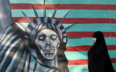 Une Iranienne promène son chien devant une fresque sur le mur de l'ancienne ambassade américaine à Téhéran, le 9 novembre 2016. (Crédit : AFP/Atta Kenare)