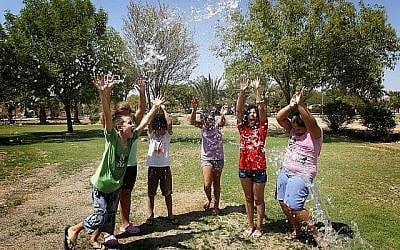 Illustration : De jeunes enfants israéliens jouent avec l'eau au kibboutz Gilgal, situé dans la vallée du Jourdain, le 15 juillet 2012. (Miriam Alster/Flash90)