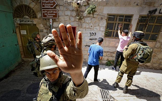 Photo d'illustration. Un soldat israélien tente de bloquer la prise de vue d'un photographe lors de la recherche d'hommes palestiniens dans la ville de Hébron, en Cisjordanie, le 22 juin 2017 (Crédit : Wisam Hashlamoun/Flash90)