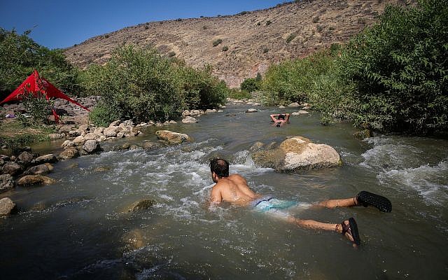 De jeunes Israéliens se rafraîchissent dans un ruisseau sur les hauteurs du Golan, dans le nord d'Israël, le 10 août 2018. (David Cohen / Flash90)