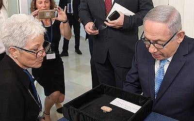 Le Premier ministre Benjamin Netanyahu et Amanda Weiss, directrice du Musée des terres bibliques à Jérusalem, avec une tablette d'argile vieille de 2 600 ans portant le nom de "Benayahu ben Netanyahu" prêtée au Bureau du Premier ministre pour l'année prochaine, le 21 août 2018 (Crédit : GPO)