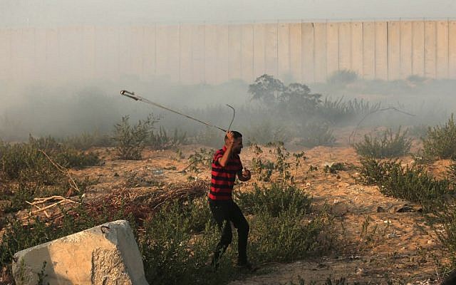 Un Palestinien utilise une fronde pour lancer une pierre contre un soldat israélien, près du point de passage d'Erez, à Gaza, le 4 septembre 2018. (Crédt : AFP/Mahmud HAMS) Un Palestinien utilise une fronde pour lancer une pierre contre un soldat israélien, près du point de passage d'Erez, à Gaza, le 4 septembre 2018. (Crédt : AFP/Mahmud HAMS)