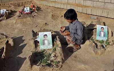 Un petit yéménite fait une prière près des tombes des enfants tués lorsqu'un bus a été touché par une frappe aérienne dirigée par les saoudiens  qui a visé le marché de Dahyan la veille dans la province de Saada, bastion des Houthis, photo prise le 4 septembre 2018 (Crédit : AFP PHOTO / STRINGER)