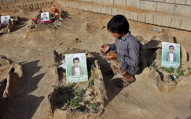 Un petit yéménite fait une prière près des tombes des enfants tués lorsqu'un bus a été touché par une frappe aérienne dirigée par les saoudiens  qui a visé le marché de Dahyan la veille dans la province de Saada, bastion des Houthis, photo prise le 4 septembre 2018 (Crédit : AFP PHOTO / STRINGER)