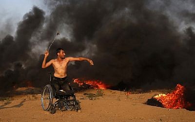 Un manifestant palestinien sur une chaise roulante jette une pierre vers les forces israéliennes durant des affrontements sur la clôture frontalière avec Gaza, à l'est de Gaza City, le 28 septembre 2018 (Crédit : / AFP PHOTO / Said KHATIB)