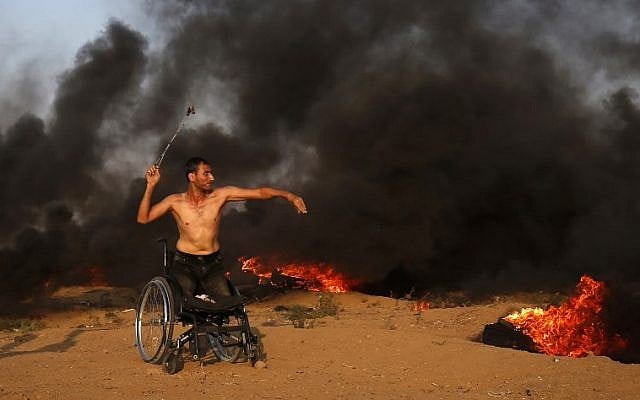 Un manifestant palestinien sur une chaise roulante jette une pierre vers les forces israéliennes durant des affrontements sur la clôture frontalière avec Gaza, à l'est de Gaza City, le 28 septembre 2018 (Crédit : / AFP PHOTO / Said KHATIB)