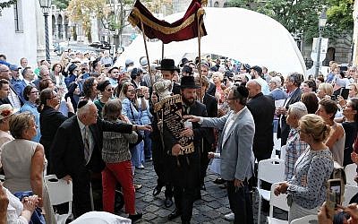 Le rabbin Asher Faith transporte un rouleau de Torah tout juste consacré pour la congrégation, lors de la consécration de l'espace de prière de la synagogue médiévale de Budapest, le 6 septembre 2018 (Crédit : Márton Merész)